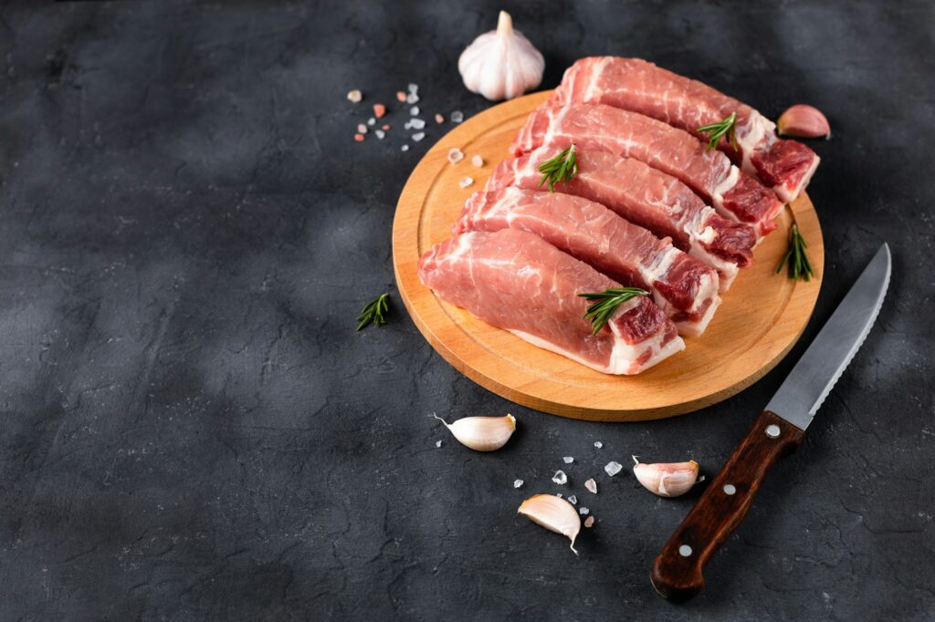 A pieces of raw fresh pork with salt on a cutting board on dark background. Meat with spices