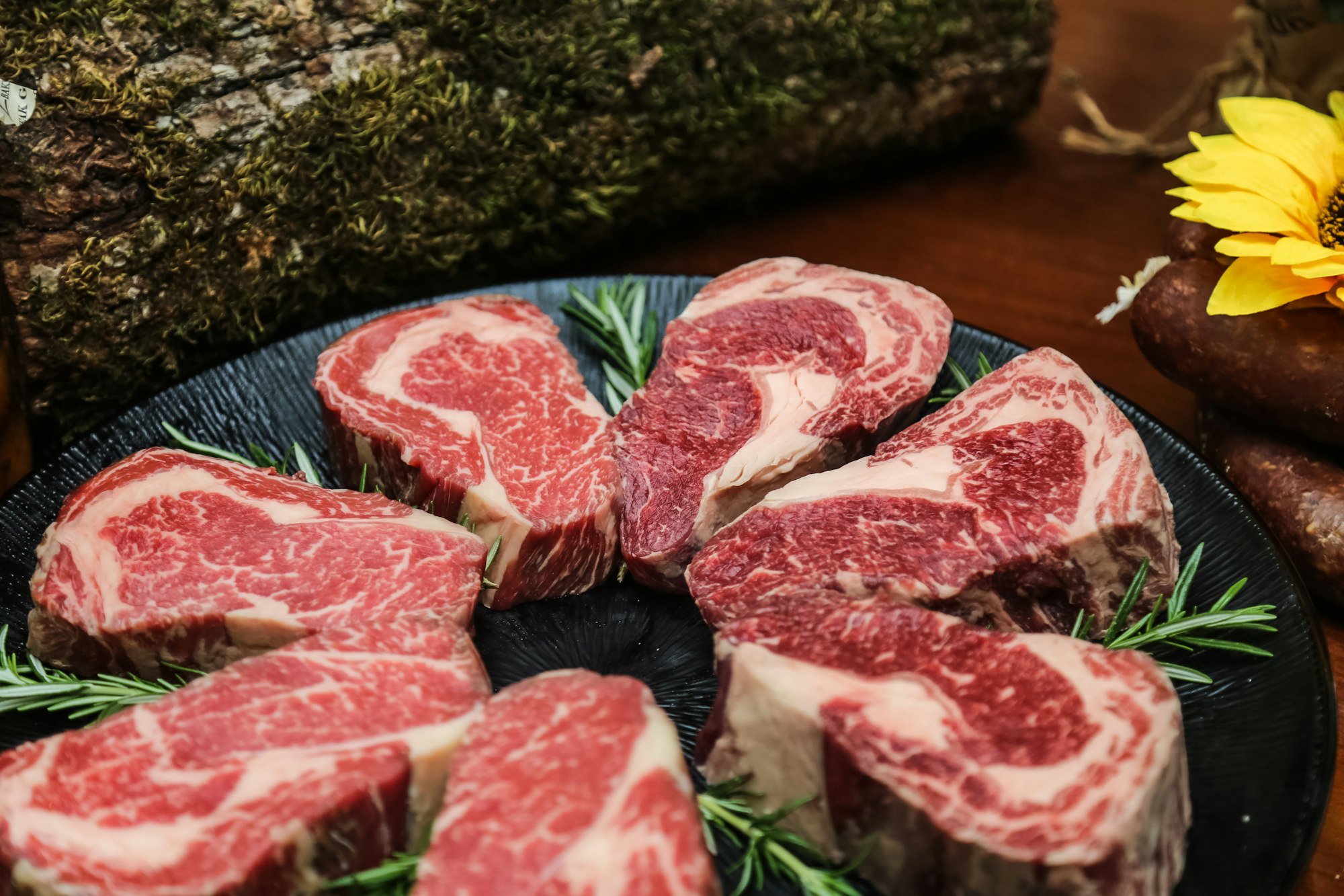 side view raw marbled steak meat with rosemary on a stand