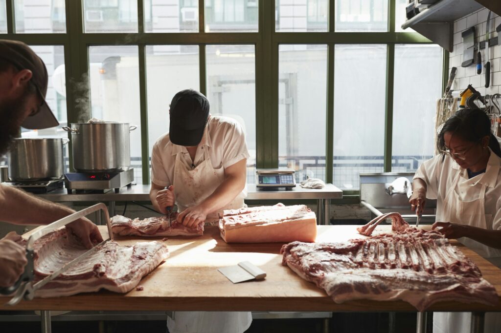 Three butchers preparing pork at a butcher's shop