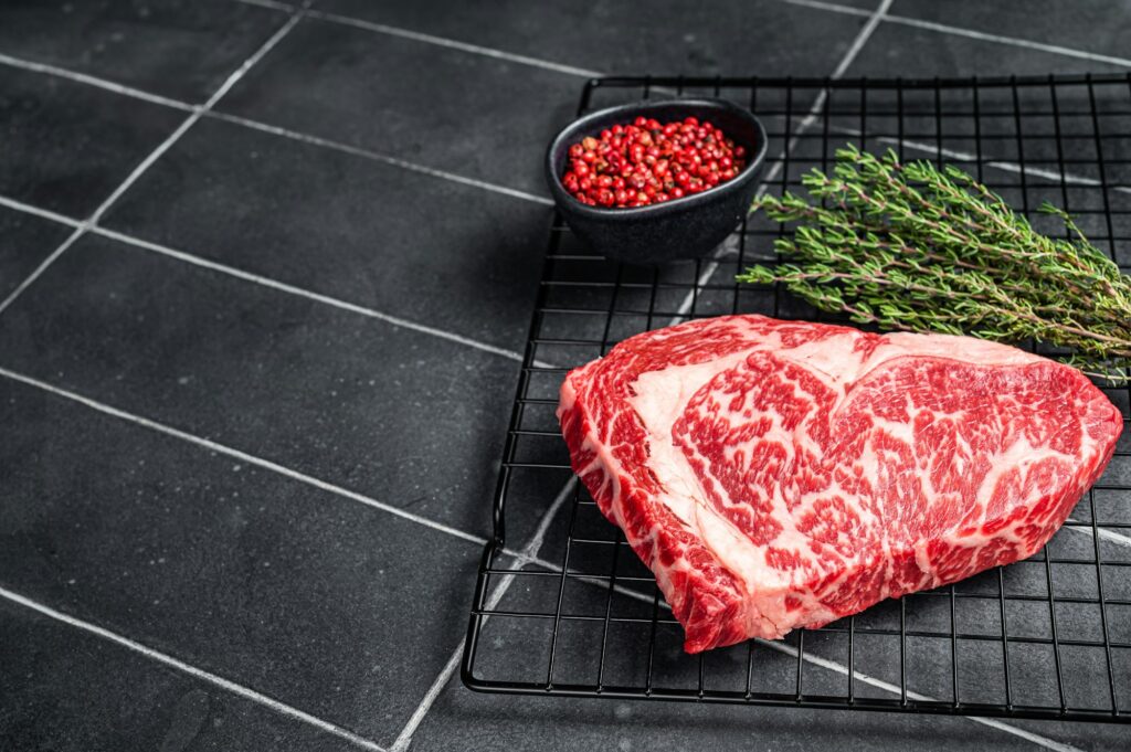 Uncooked wagyu Rib Eye steak, raw beef meat. Black background. Top view. Copy space
